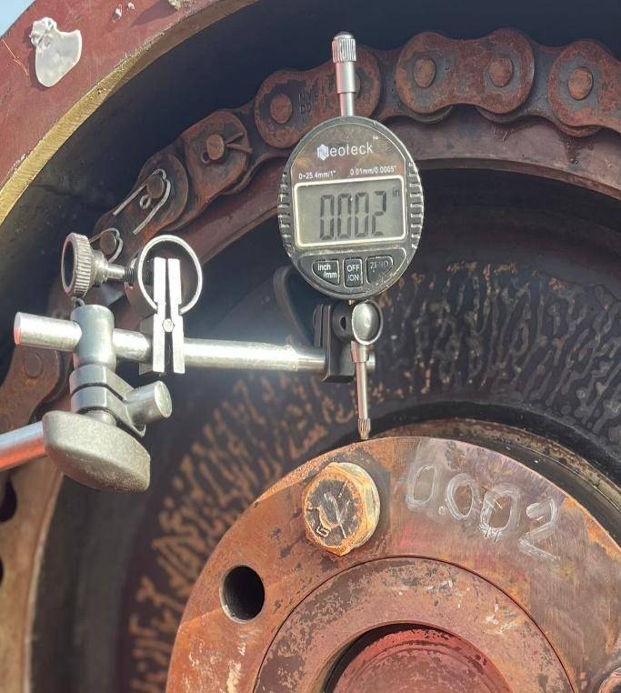 Reloj comparador digital marcando 0,002 pulgadas junto a la medida 0,002 escrita sobre la brida de la bomba de lodo