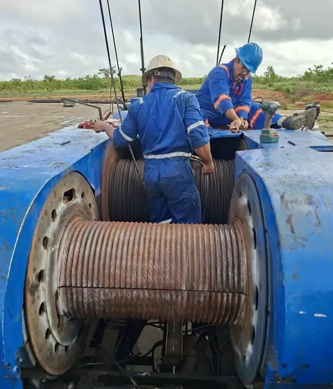 Dos técnicos sobre el tambor con cable, en el taladro